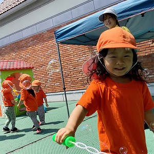 シャボン玉遊びで笑顔を見せる子ども