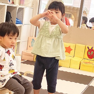 指でハートの形を作って見せる子ども