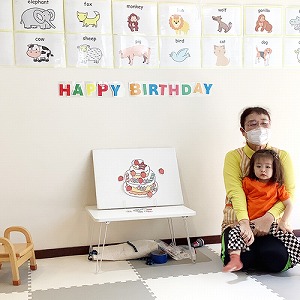 先生の膝に乗り、6月のお誕生日を祝われる子ども