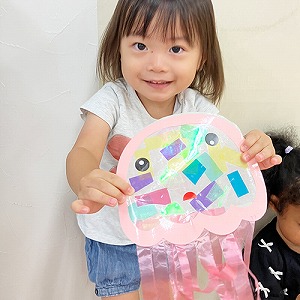 作品のくらげを笑顔で見せる子ども