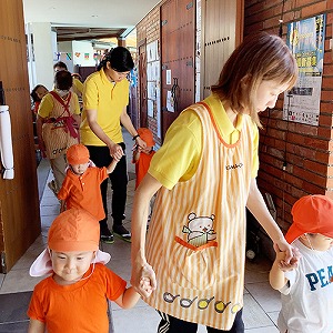 先生と手を繋いで屋外へ避難する子どもたち