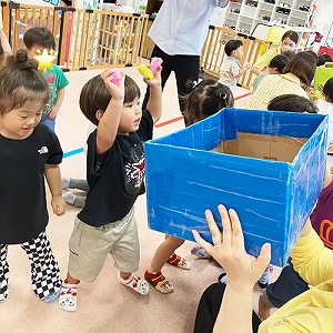 先生が持つ箱に玉を入れる子どもたち