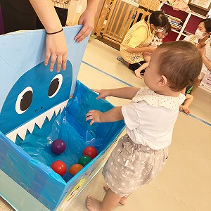 サメの口にボールを入れる子ども