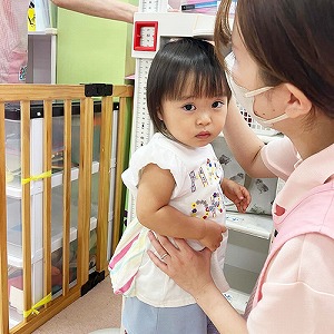 先生に支えられながら緊張の面持ちで身長を計る子ども