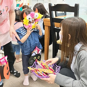 ハロウィーンのお面をつけてお菓子をもらう子どもたち