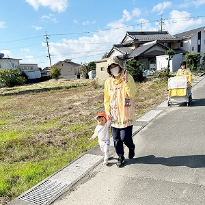 子どもと手をつないで歩く保育士とお散歩カートを押す保育士