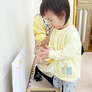 手作り賽銭箱にコインを入れた後に手を合わせる子ども