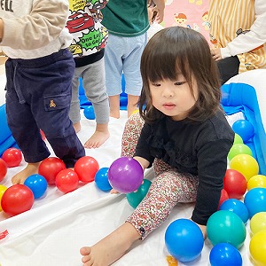 ボールプールの中でボールを持つ子ども