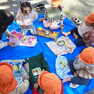 公園で輪になってお弁当を食べる子どもたち